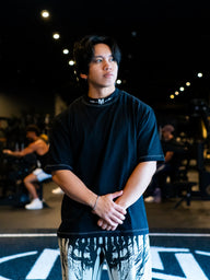 Model wearing the Fear of None Premium oversized tee in black, front view in the gym
