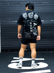 Model from behind wearing the Sacrifice Premium oversized tee in black with demon mask print, in the gym