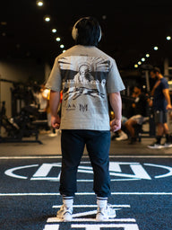 Model from behind wearing the Death Whistle Premium oversized tee in snakestone, in the gym