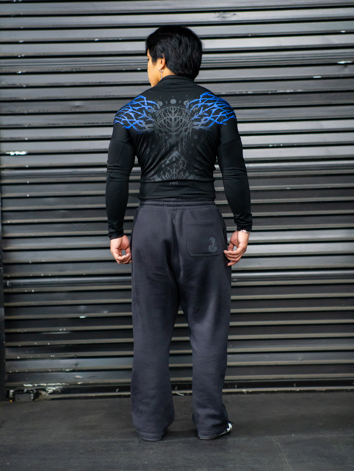 Back of the Nine Worlds compression quarter zip in black with blue tribal shoulder print, worn — second view