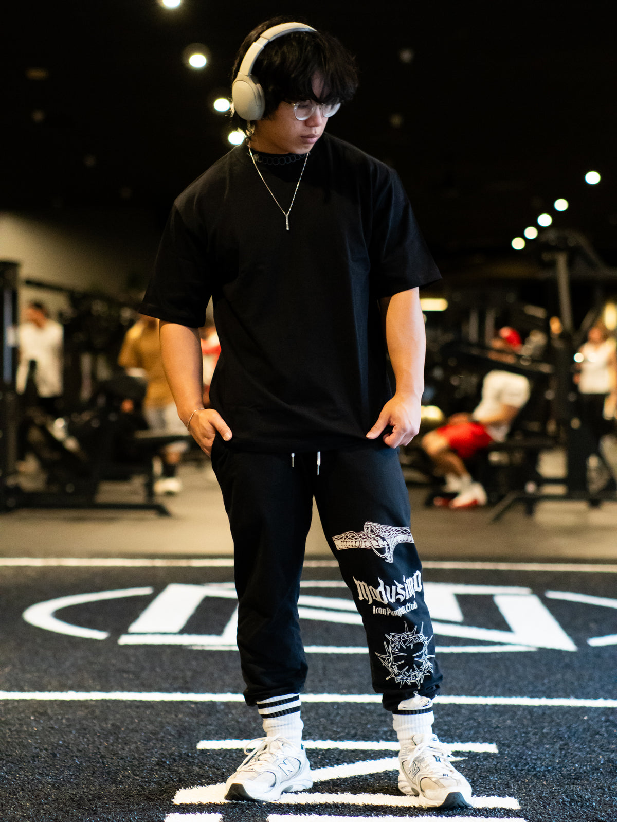 Model wearing the Strength and Power Premium oversized tee in black, front view in the gym — second view