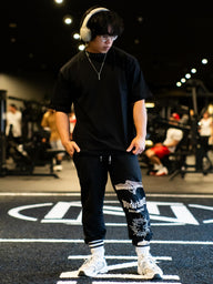Model wearing the Strength and Power Premium oversized tee in black, front view in the gym