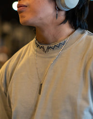 Collar detail with neck logo on the Death Whistle Premium oversized tee in snakestone, worn