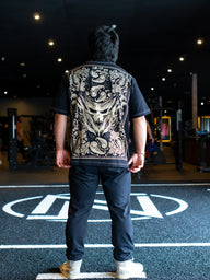 Model from behind wearing the Strength Within Premium oversized tee in black, in the gym