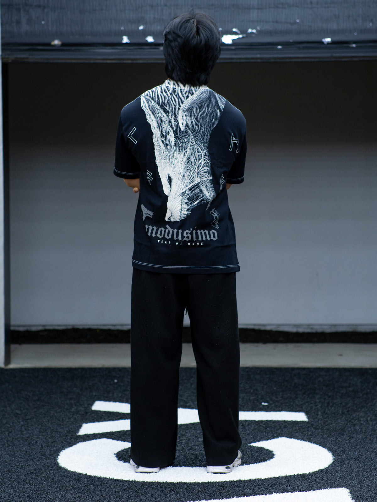 Model from behind wearing the Fenrir Premium oversized tee in black with white wolf back print — second view