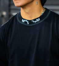 Collar detail with neck logo on the Warmonger Premium oversized tee in black, worn