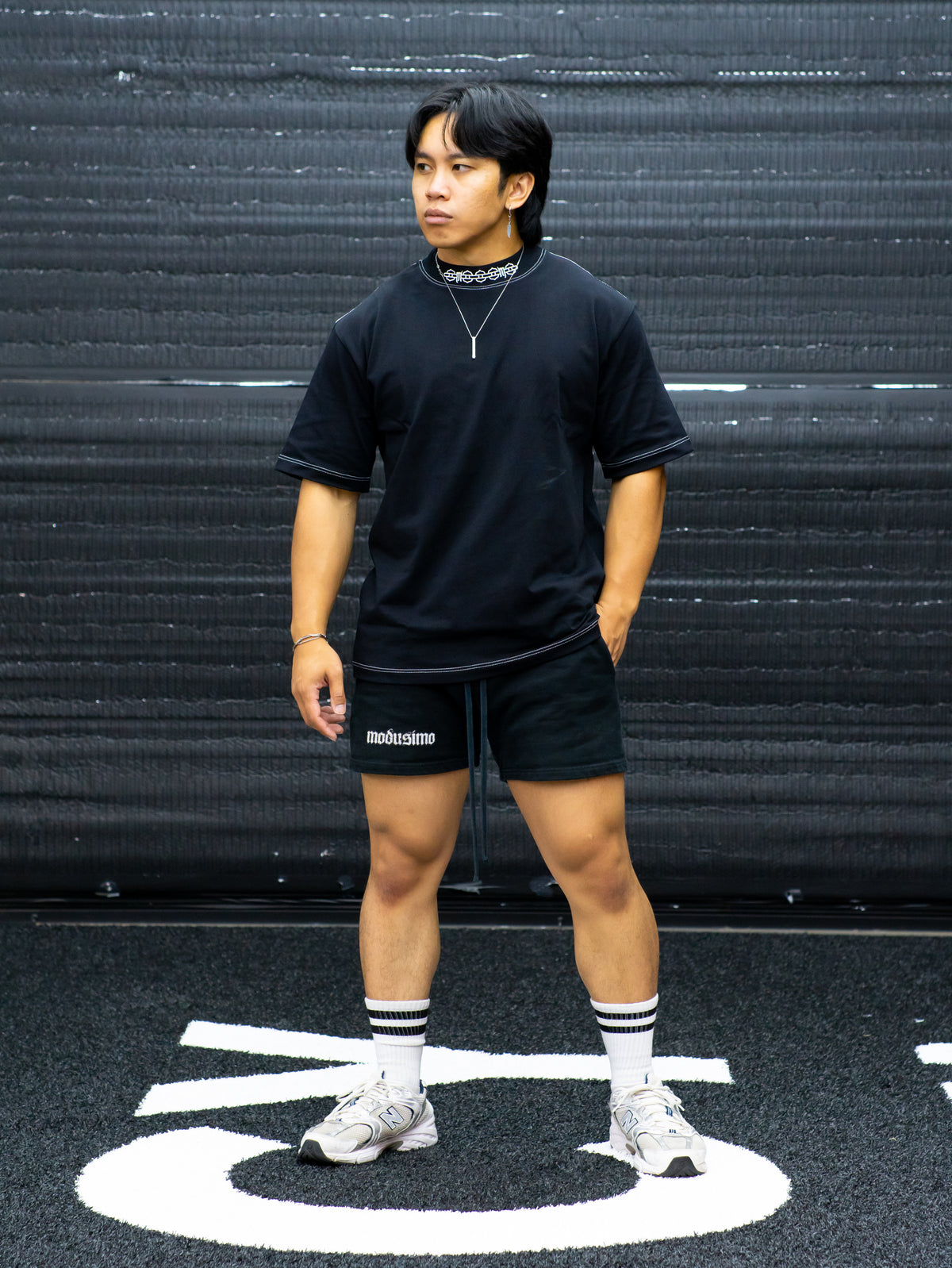 Model wearing the Sacrifice Premium oversized tee in black with black shorts, front view — second view