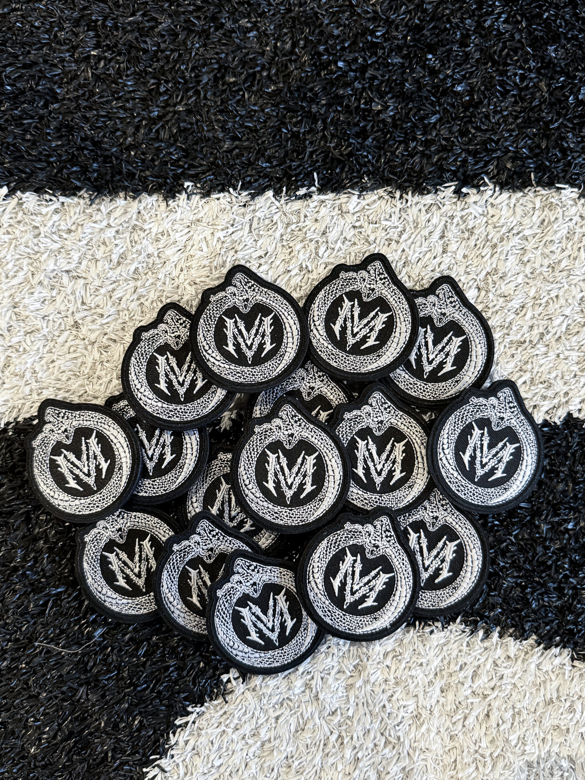 Pile of Infinity velcro patches with the Modusimo monogram in black and silver — second view