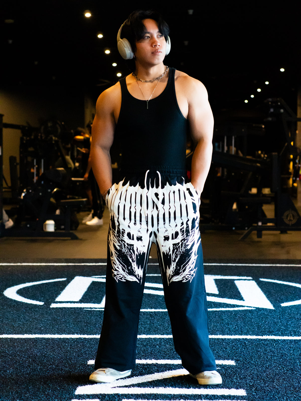 Model wearing the I Rise Again sweatpants in black with white wing print and a black tank top — second view
