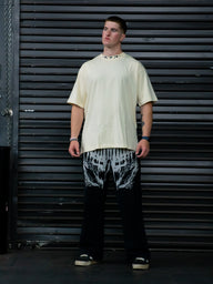 Model wearing the Thunder Premium oversized tee in pastel cream with black printed pants, front view