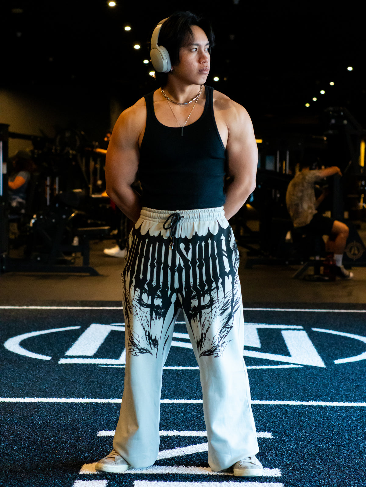 Model wearing the I Rise Again sweatpants in cloud gray with black wing print and a black tank — second view