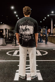 Model from behind wearing the Ashes to Ashes Premium oversized tee in black, in the gym