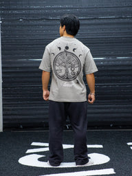 Model from behind wearing the Chase the Night Premium oversized tee in snakestone, in the gym