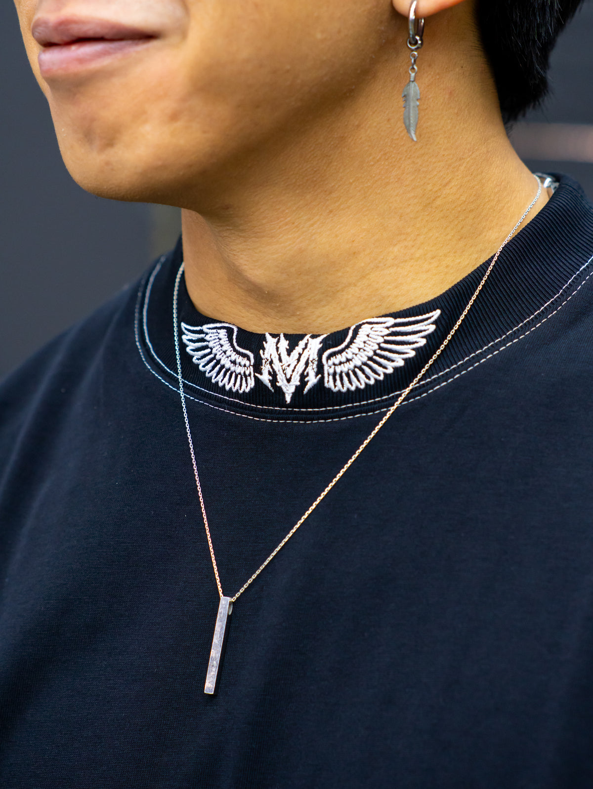 Collar detail with winged neck print on the Ragnarok Premium oversized tee in black, worn — second view