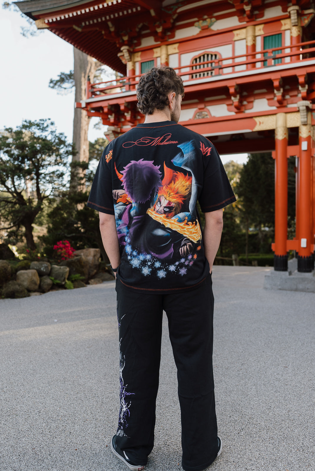 Model from behind wearing the Ablaze Premium oversized tee in black at a red shrine gate — second view