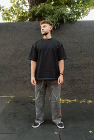 Model wearing the Motivated Premium oversized tee in black with gray jeans, full length front view
