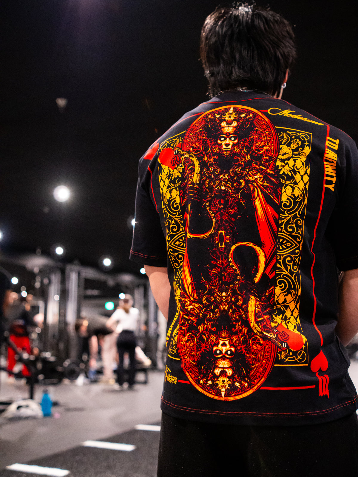 Close-up of the Luck of the Draw red and gold card back print on the black Premium tee, worn — second view