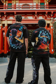 Two models from behind wearing the Ablaze and Set Your Heart Premium oversized tees in black at a red shrine gate